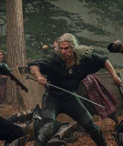 Geralt wields a sword and axe as soldiers attack him on each side in a fight scene from The Witcher season 3